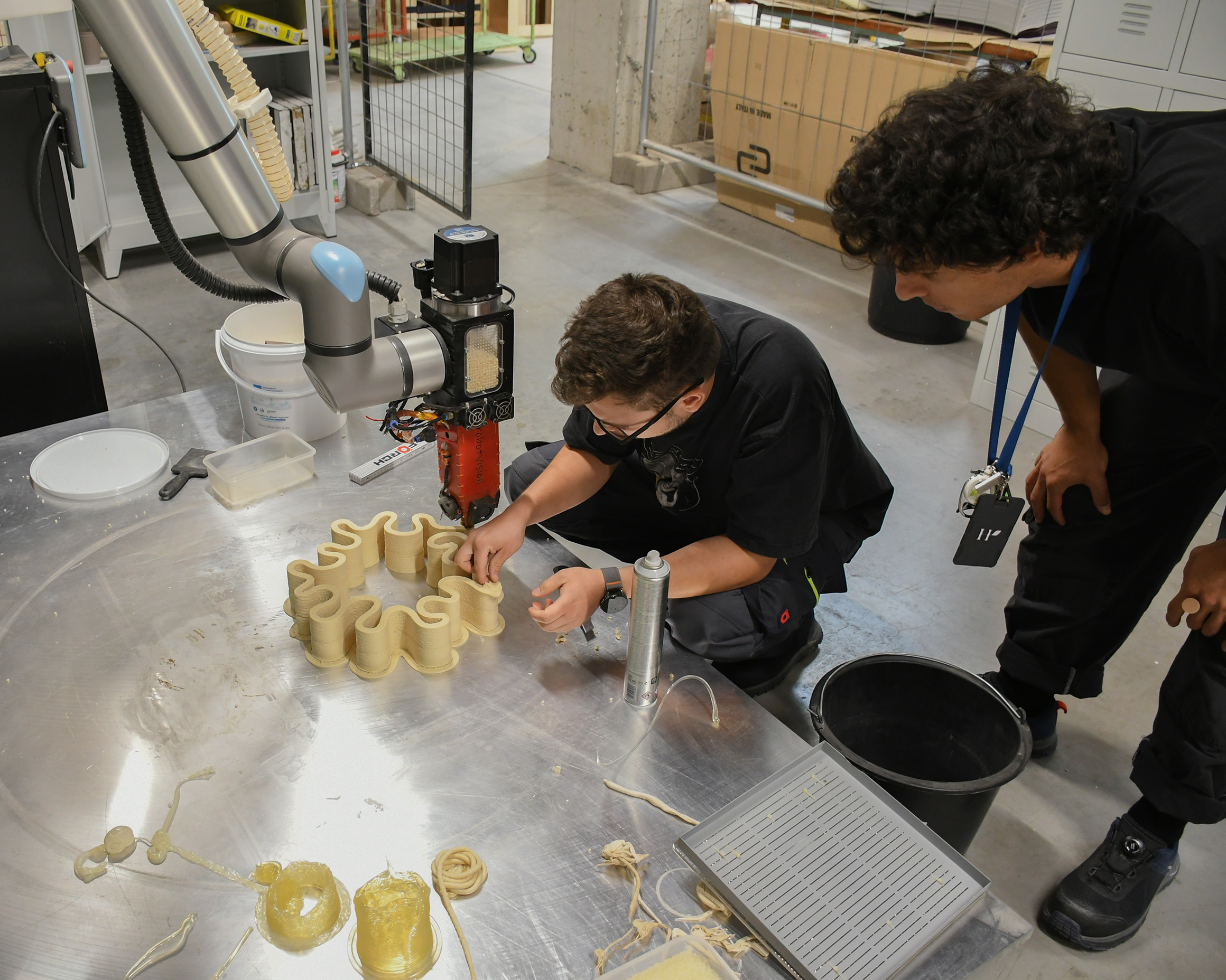 mkt team checking 3D-printed samples next to a robotic printer
